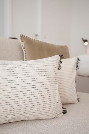 Primer plano de un sofá con almohadones a rayas y un cojín liso.
