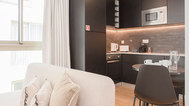 Ein modernes Hotelzimmer mit einer Couch, einem Esstisch und einer Küchenzeile.