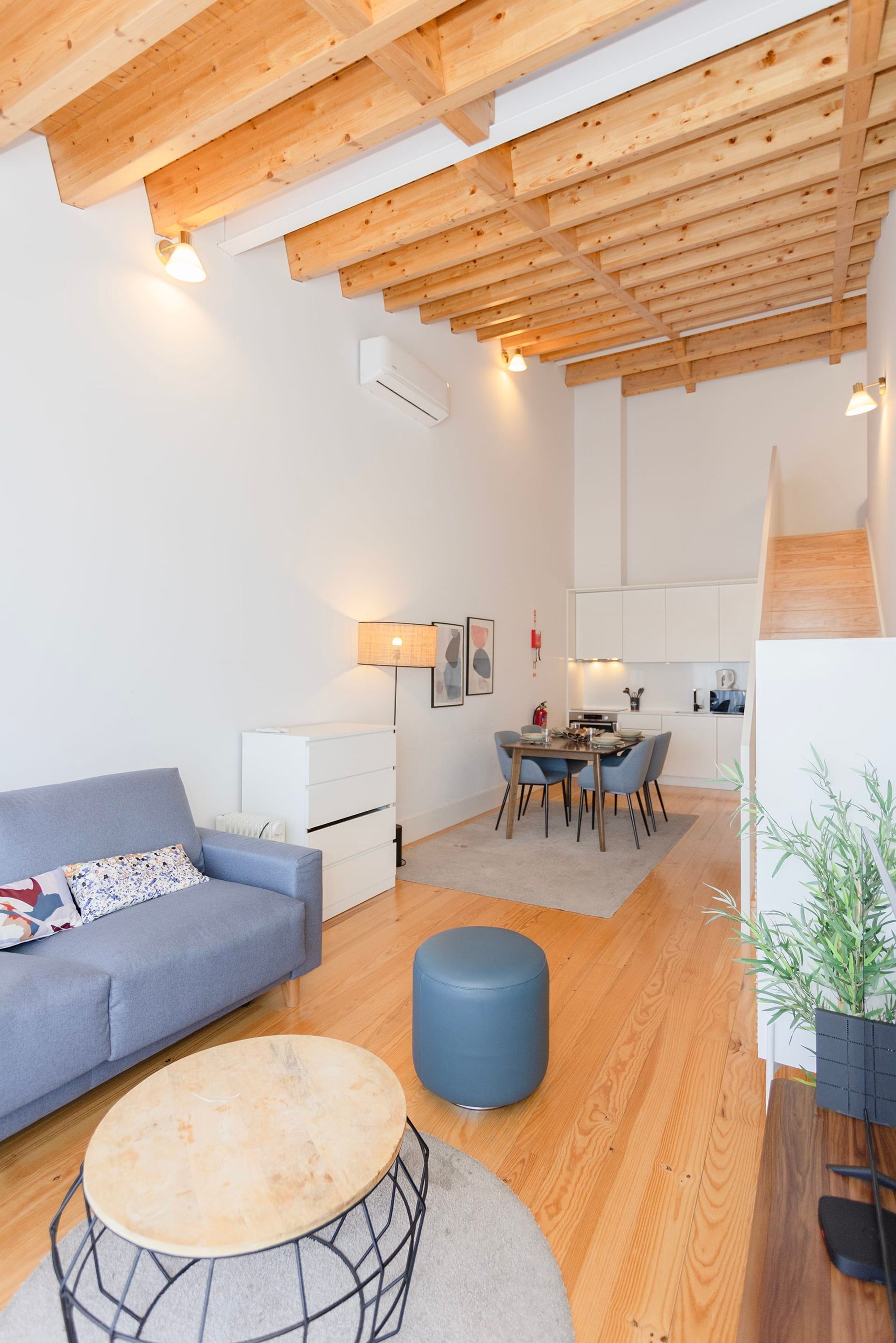 A modern living room with a sofa, a round coffee table, and a dining area with chairs and a table.