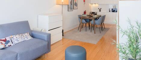 A modern living room with a sofa, a round coffee table, and a dining area with chairs and a table.
