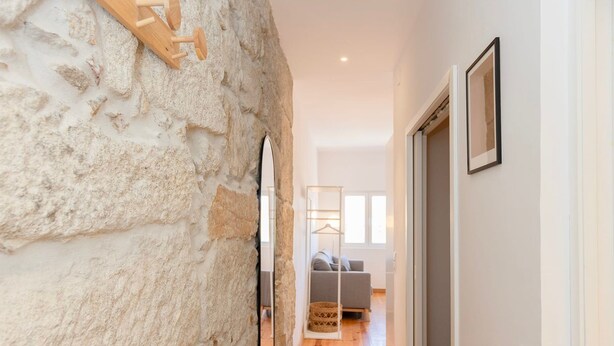 Un pasillo con pared de piedra, suelo de madera y una cama al fondo.