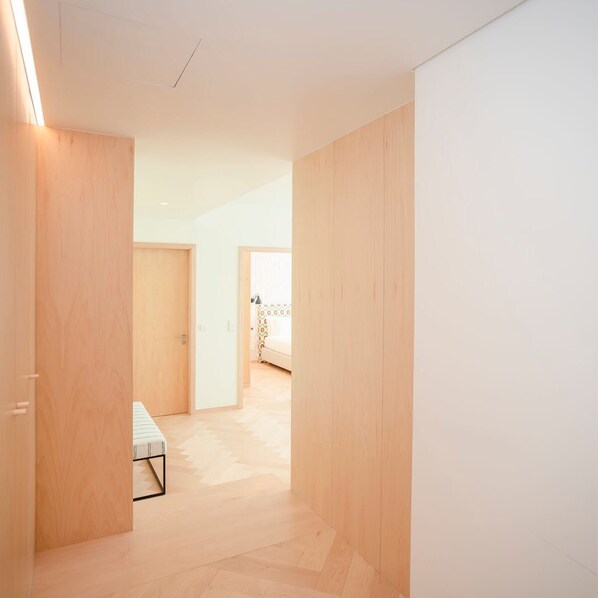 A hallway with wooden walls and floors, leading to a room with a bed and a patterned curtain. - Allegro Boutique Apartment 1A by Liiiving (Porto)