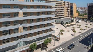 A multi-story building with a modern architectural design, featuring a mix of glass and brick facades, and a parking area with a bus stop. - Allegro Boutique Apartment C by Liiiving (Porto)