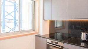 A modern kitchen with a built-in oven, a coffee maker, and a window with a view of a construction site. - Allegro Boutique Apartment C by Liiiving (Porto)