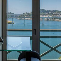 Una habitación con un amplio ventanal que ofrece vistas a un río y un puente.