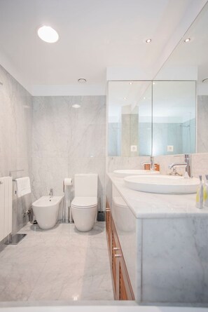 A modern bathroom with a large mirror, two sinks, a bidet, and a toilet. - Liiiving in Porto - Douro Riverside Apartment (Gondomar)