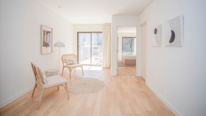 Ein geräumiges Zimmer mit Holzboden, einem runden gewebten Teppich, einem Holzstuhl und einem gerahmten Bild an der Wand.