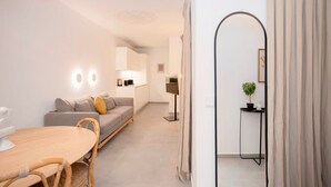 Ein modernes Wohnzimmer mit Sofa, Esstisch und einer kleinen Küchenzeile.