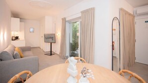 Ein modernes Wohnzimmer mit einer Couch, einem Esstisch mit Stühlen, einem Fernseher und einem Schild mit der Aufschrift 'LIVING'.