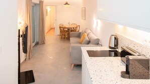 Eine moderne Küche mit Arbeitsplatte, Spüle und Kaffeemaschine. Ein Essbereich mit Tisch und Stühlen ist ebenfalls vorhanden.