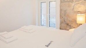 Ein Hotelzimmer mit Bett, Fenster und Steinwand.