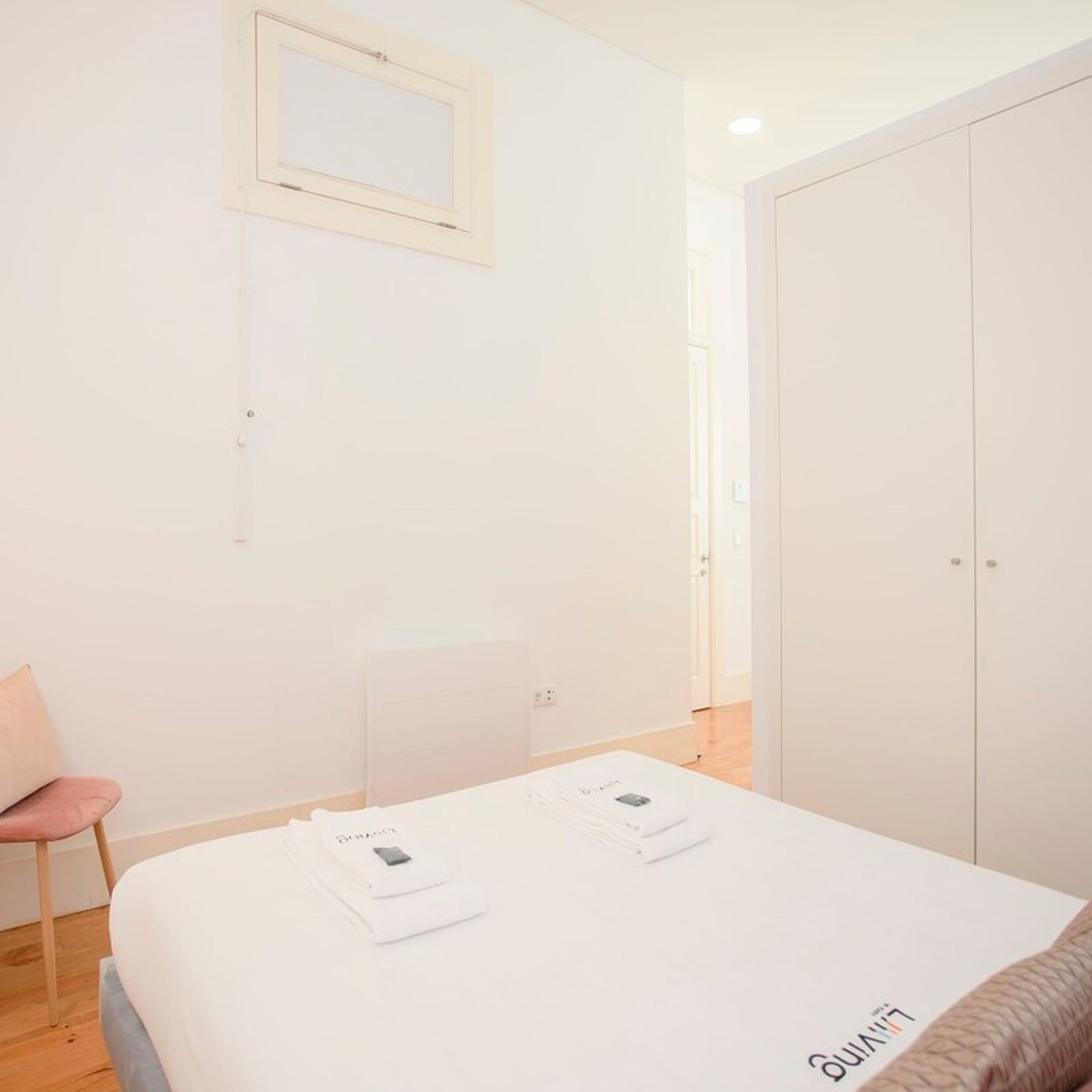 Une chambre à coucher au style minimaliste, avec un lit, une chaise et une armoire.