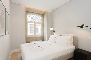 Un dormitorio con una cama grande, una ventana con vistas, una mesita de noche y una lámpara.