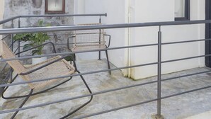 Ένα μπαλκόνι με πέτρινο τοίχο, μεταλλική μπαλκονιέρα και έπιπλα από μπαμπού.