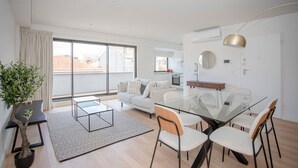 En moderne lejlighed med et glasbord, en hvid sofa og en potteplante.