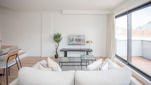 A modern living room with a sofa, a dining table, and a TV. - Liiiving in Porto - City Design Apartment Q (Porto)