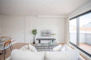 A modern living room with a sofa, a dining table, and a TV.