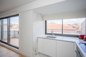 A modern kitchen with a large window, sliding glass door, and a view of buildings. - Liiiving in Porto - City Design Apartment Q (Porto)