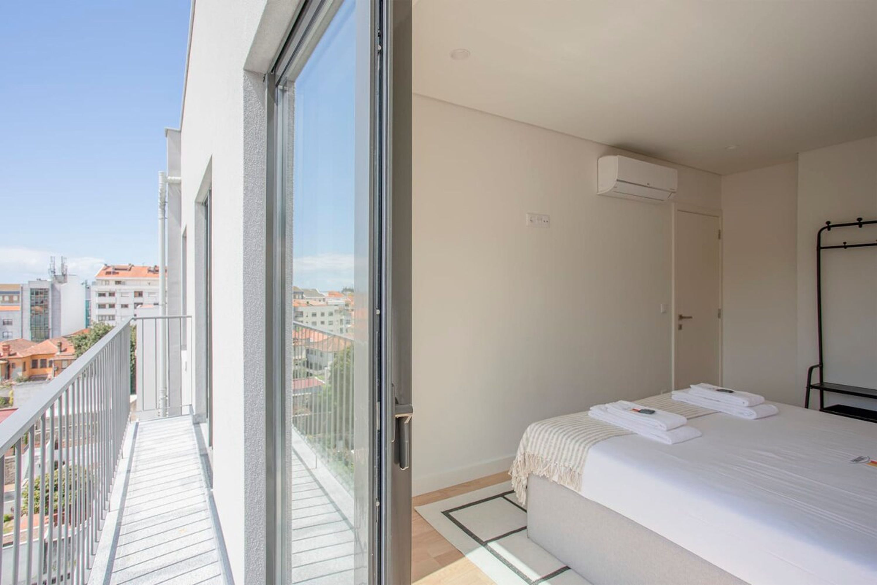 A hotel room with a balcony, a bed with towels, and an air conditioning unit.