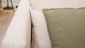A modern living room with a sofa and a green pillow, a floor lamp, and a kitchen in the background. - Liiiving in Porto - Uptown Pearl Apartment (Porto)