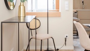 A modern room with a desk, chair, and a large mirror. There is a window with a view of the outside, a lamp, and a plant on the desk. - Liiiving in Porto - Uptown Pearl Apartment (Porto)
