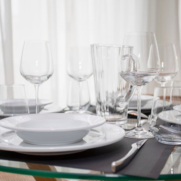 A table set with white plates, clear glasses, and a pitcher of water, suggesting a dining area. - Liiiving in Porto - Modern Glam Apartment J (Porto)