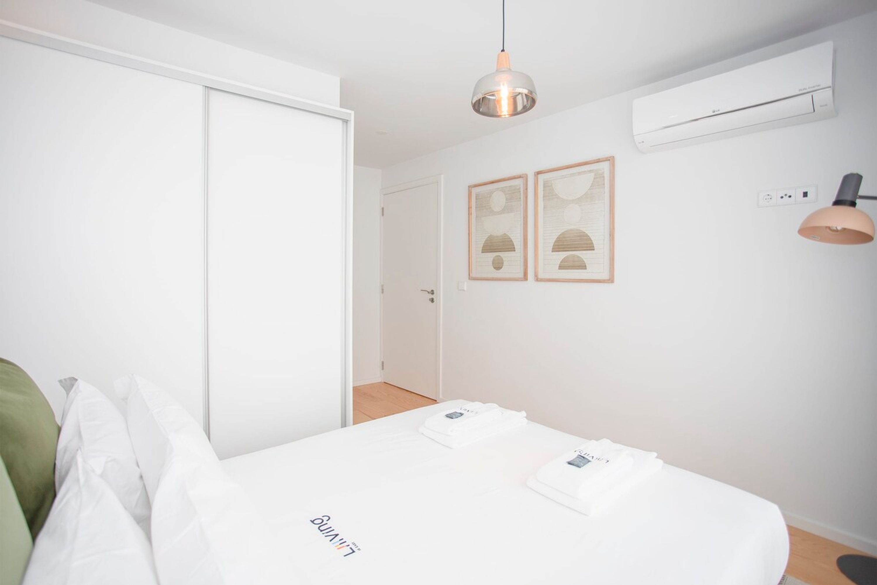 Una camera da letto con un letto, un armadio, una lampada a sospensione e due condizionatori fissati al muro.