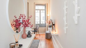 A hallway with a large mirror, a vase with red flowers, a small table with a candle, and a chair. - Liiiving in Porto - Chic Sweet Home (Porto)