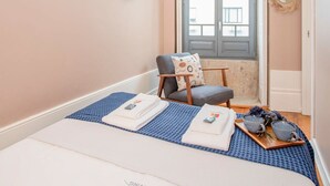 A bedroom with a bed, a chair, a window, and a wall-mounted decoration. - Liiiving in Porto - Chic Sweet Home (Porto)
