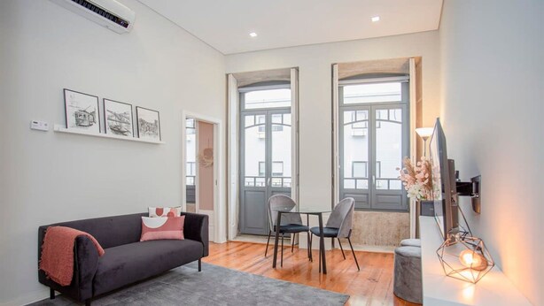 A modern living room with a black sofa, a grey rug, and a dining area with chairs and a table. - Liiiving in Porto - Chic Sweet Home (Porto)