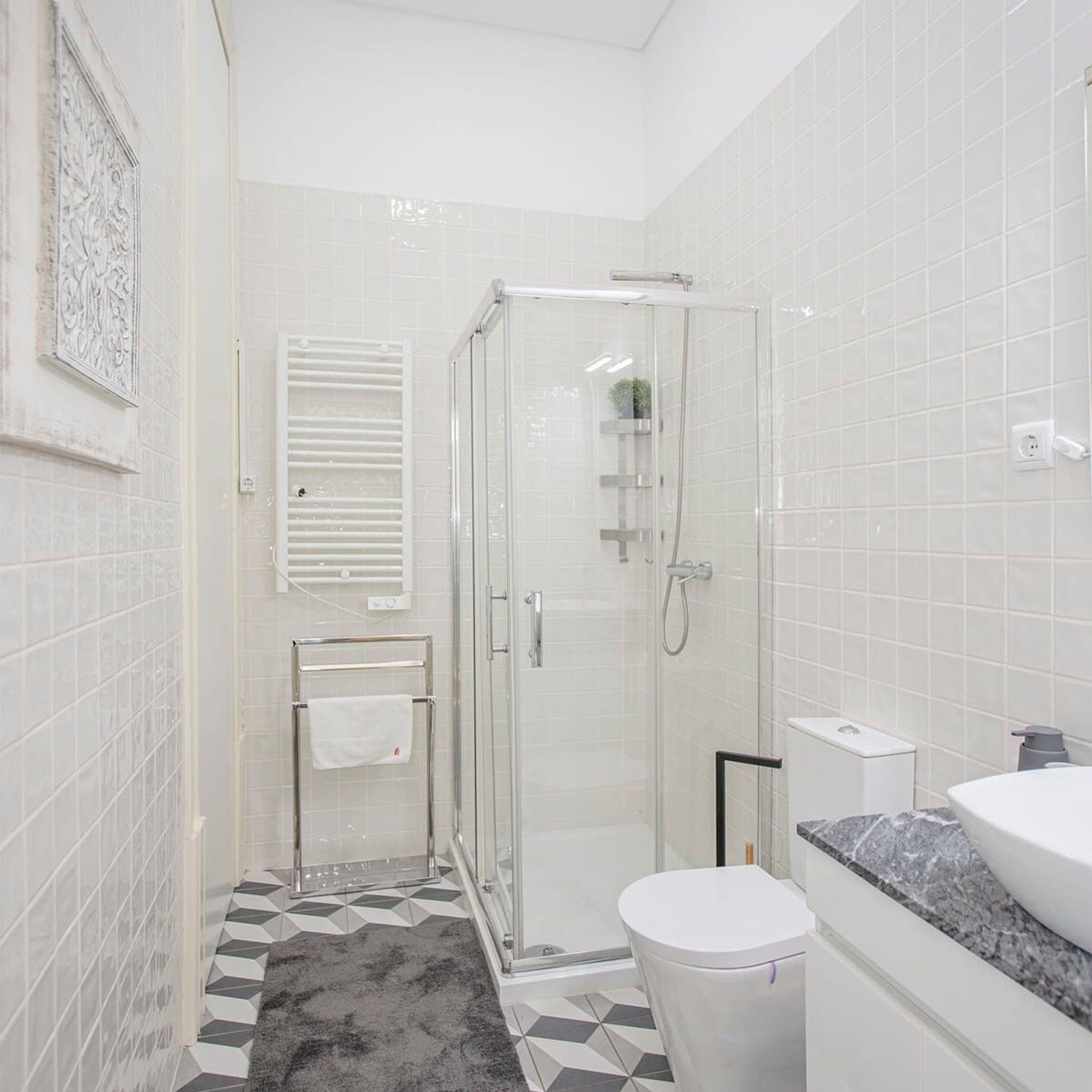 Une salle de bain moderne avec une douche à parois de verre, des toilettes blanches et un lavabo doté d’un plan de travail en marbre.