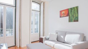 A modern living room with a white sofa, a matching ottoman, and a painting on the wall. - Liiiving in Porto-mouzinho Residence Apartment 3F (Porto)