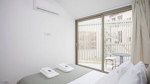 A hotel room with a bed, a window with a view of a balcony, and an air conditioning unit. - NAX Apartment G by Liiiving (Porto)