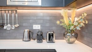 A modern kitchen with a microwave, kettle, toaster, and a vase with dried plants. - NAX Apartment G by Liiiving (Porto)