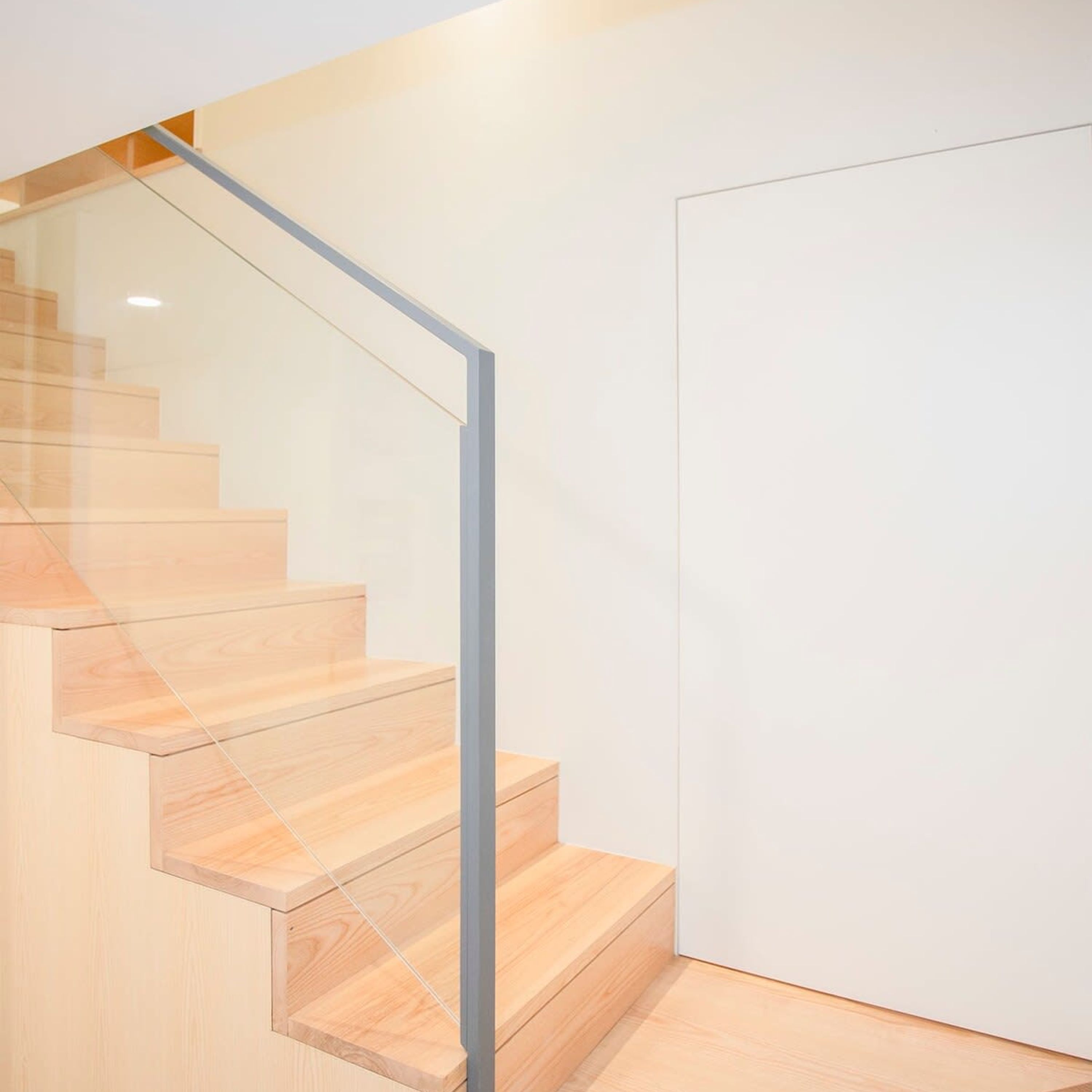 Una moderna scala con gradini in legno e ringhiera in vetro.