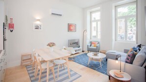 A modern living room with a dining area, a sofa, a TV, and large windows. - Liiiving in Porto - Haven Pool Apartment (Porto)