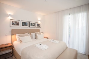 A hotel room with a large bed, a bedside table, a nightstand, and a window with sheer curtains. - Liiiving in Gaia - Cooper Residence Apartment II (Vila Nova de Gaia)