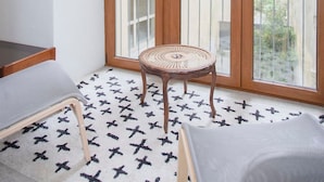 A balcony with a wooden door, a wicker chair, and a patterned rug. - Liiiving in Porto - Oasis Retreat Apartment (Porto)