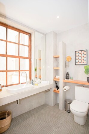 A modern bathroom with a large window, a white sink, a toilet, and a small trash bin. - Liiiving in Porto - Oasis Retreat Apartment (Porto)