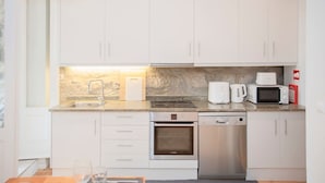 A modern kitchen with white cabinets, a built-in oven, a dishwasher, a microwave, and a coffee maker. - Liiiving in Porto - Oasis Retreat Apartment (Porto)