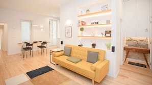 A modern living room with a sofa, a dining table with chairs, and a built-in shelf with books and decorative items. - Liiiving in Porto - Oasis Retreat Apartment (Porto)