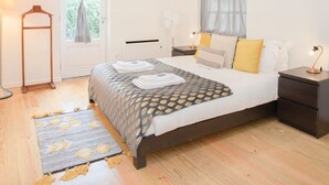 A modern bedroom with a large bed, bedside tables, a floor lamp, and a window with curtains. - Liiiving in Porto - Oasis Retreat Apartment (Porto)