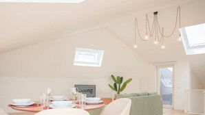 A modern loft-style living space with a dining area, a green sofa, and a dining table set for four. - Liiiving in Porto - Cedofeita Green Terrace (Porto)