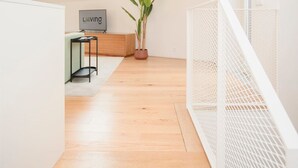 A modern loft with a sloped ceiling, a skylight, a wooden floor, a potted plant, a TV on a stand, and a white railing. - Liiiving in Porto - Cedofeita Green Terrace (Porto)
