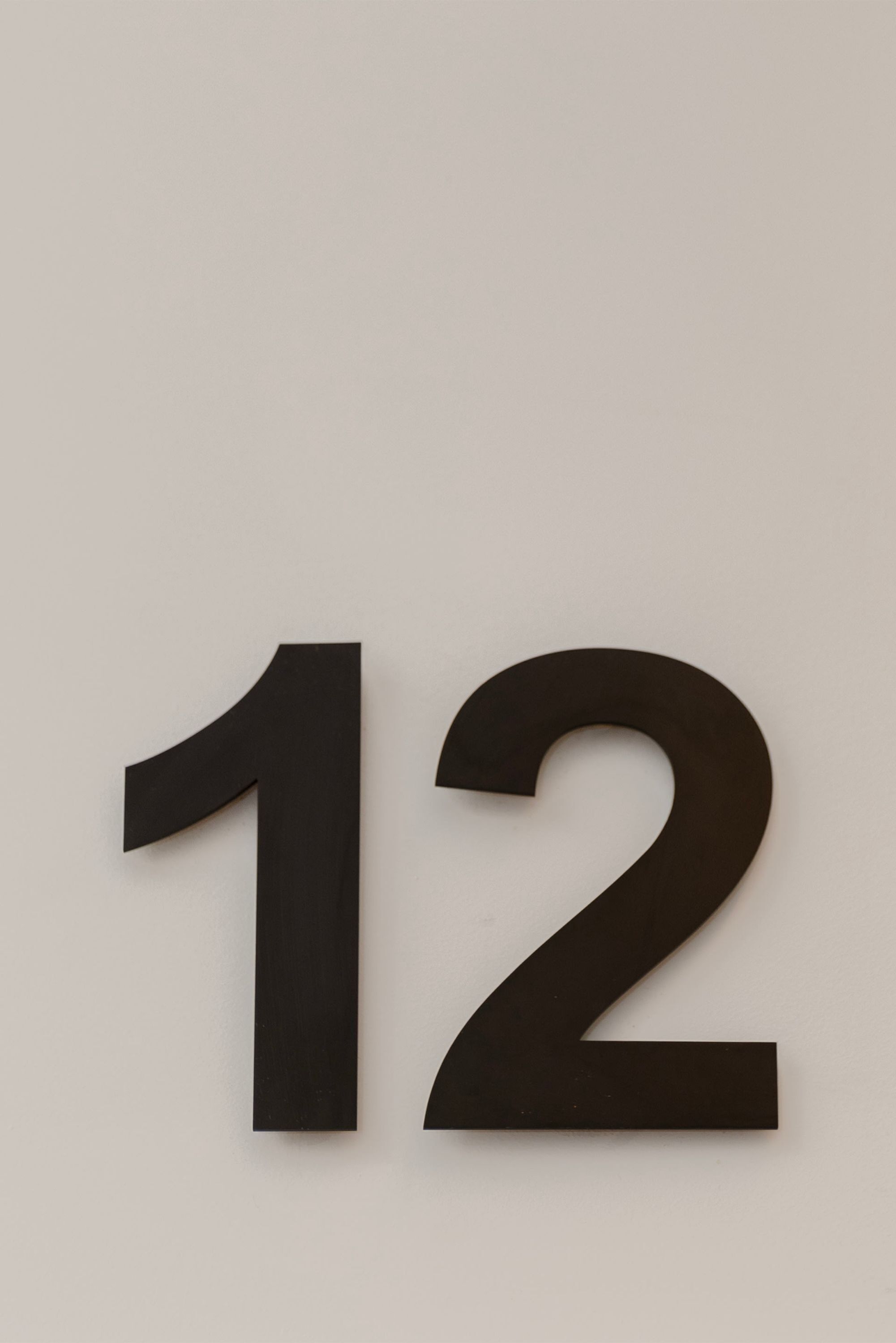 A wall-mounted number sign displaying the number 12.