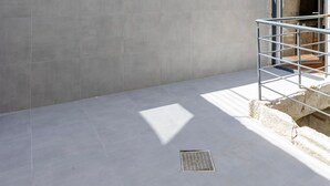 Un bâtiment moderne doté d’une façade en pierre, de grandes fenêtres et d’une cour dallée.