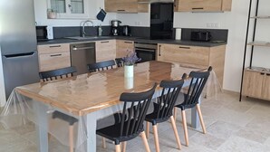 A modern kitchen with a central island, wooden cabinets, and a built-in oven. - Charming Countryside Home with Modern Amenities in Scenic Perche Hills (Melleray)