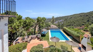 Ein Poolbereich mit Meerblick, umgeben von Grünflächen und einem Hügel.