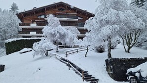 A snow-covered building with a wooden facade, a staircase leading to a balcony, and snow-laden trees. - Renovated T2 in Le Grand-Bornand with balcony, parking and terrace, 4 people, near village (Le Grand-Bornand)