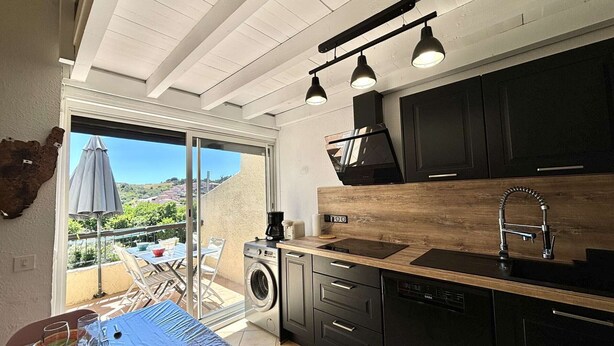 A modern kitchen with a wooden countertop, black cabinets, and a built-in oven. There is a large window providing a view of the outdoors. - 3-room apartment with pool, AC and Wi-Fi in Porticcio (Porticcio)